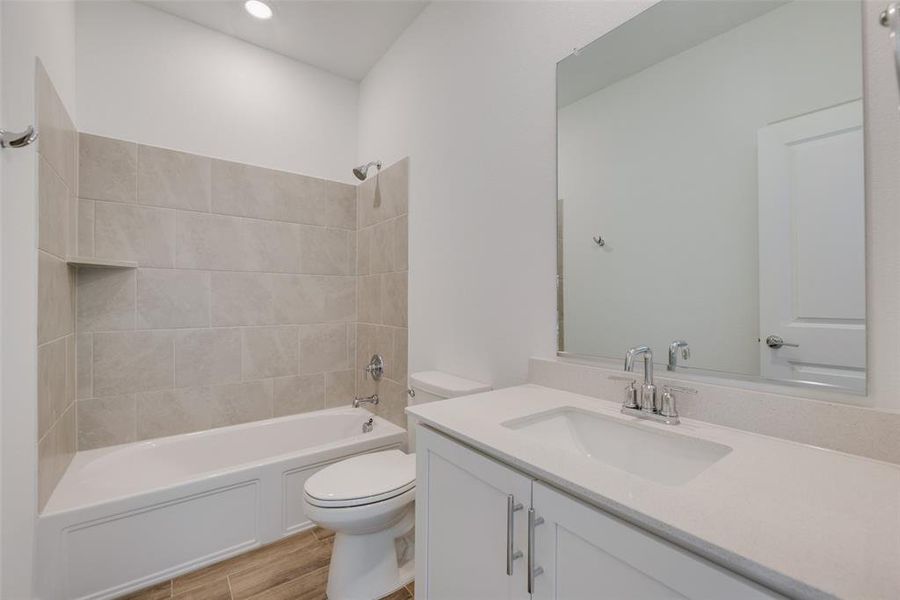 Full bathroom featuring vanity, tiled shower / bath combo, toilet, and hardwood / wood-style floors