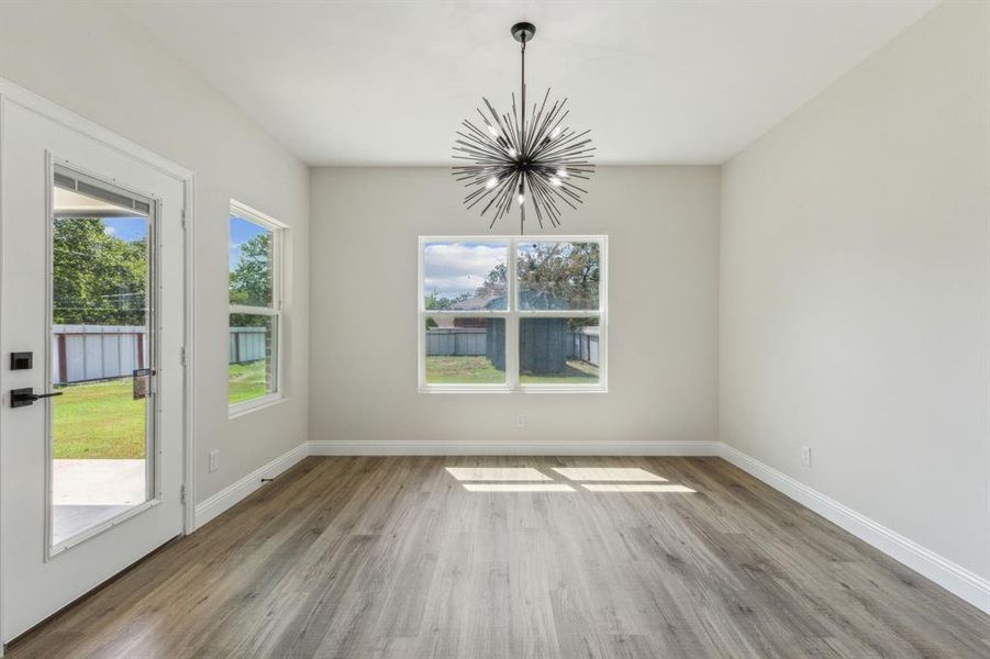 Unfurnished dining area with an inviting chandelier, light hardwood / wood-style floors, and plenty of natural light