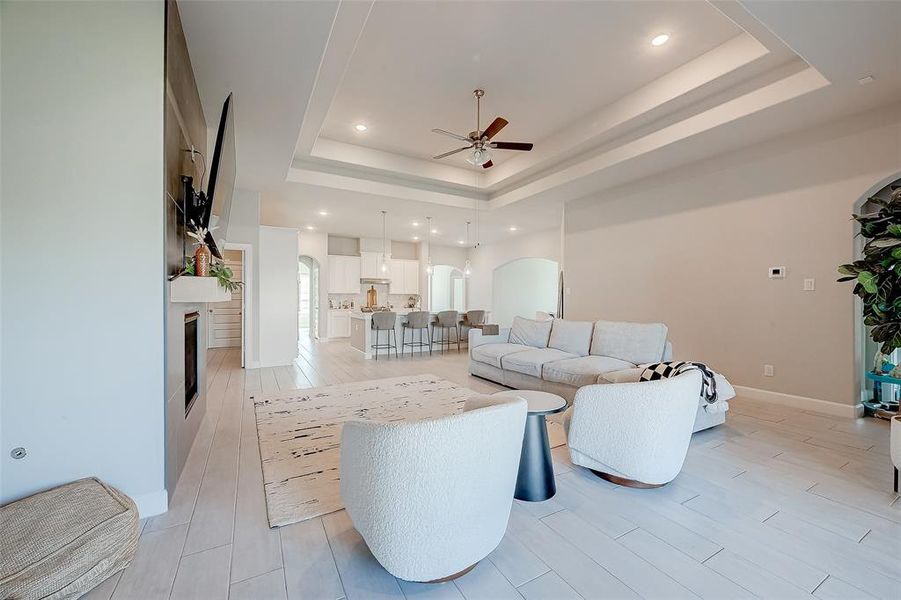 Living room features tile flooring, aceiling fan, high ceilings, and fireplace.