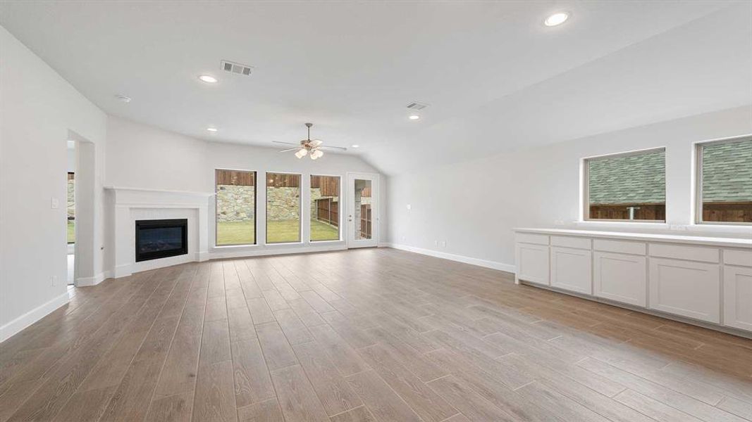 Unfurnished living room with ceiling fan, light hardwood / wood-style flooring, and lofted ceiling