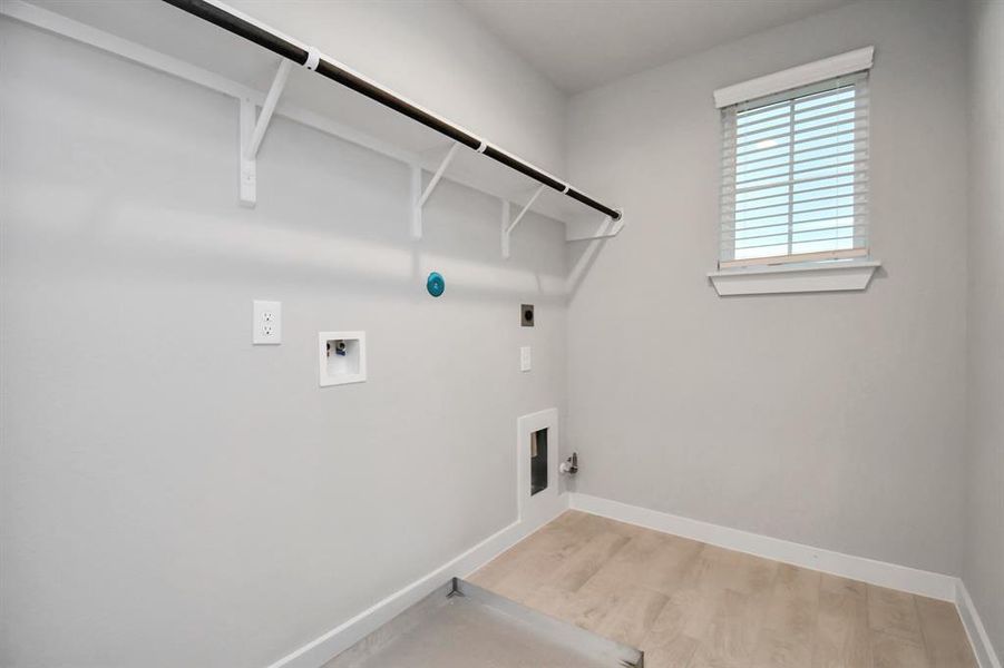 A spacious utility room with ample shelving for organization. It features connections for both gas and electric dryers, making it versatile and functional for all laundry needs.