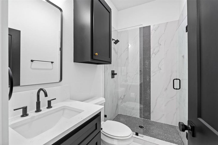 Bathroom featuring vanity, toilet, and a shower with door