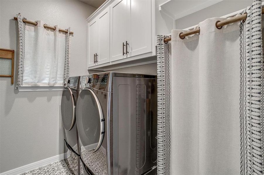 Laundry room with washer and clothes dryer, tile patterned flooring, and cabinets