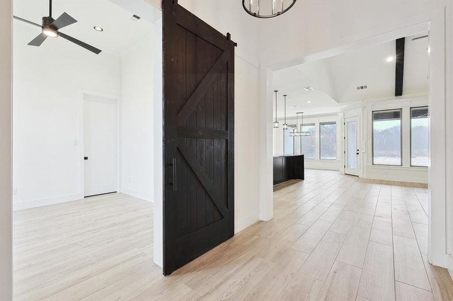 Hall with a barn door, light hardwood / wood-style floors, and an inviting chandelier