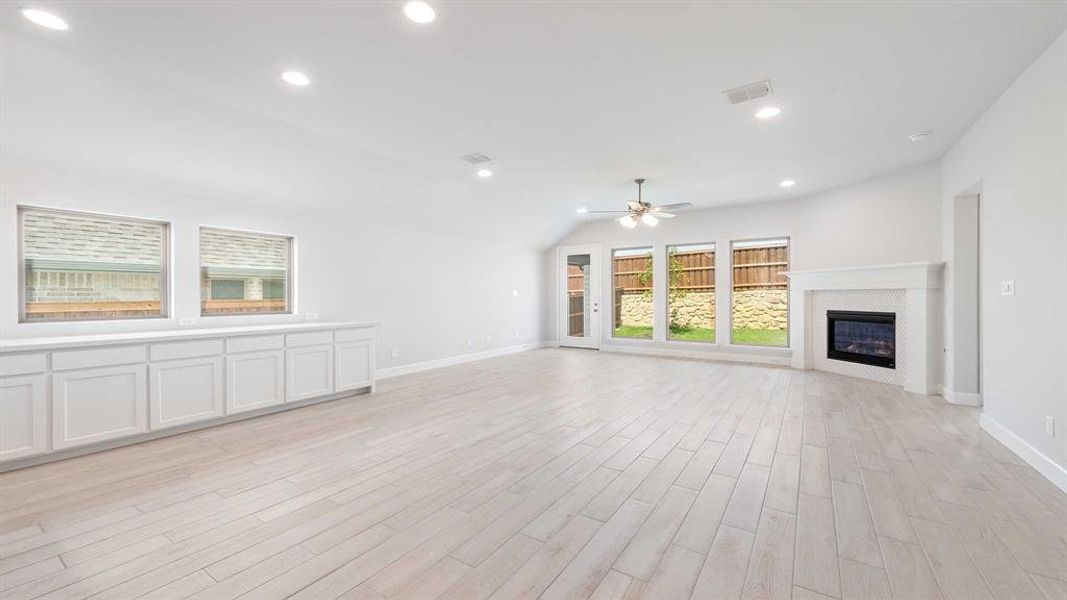 Unfurnished living room with light hardwood / wood-style flooring, ceiling fan, and vaulted ceiling