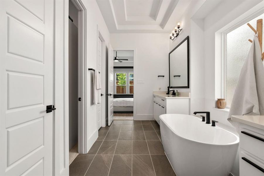 Bathroom featuring a bathing tub, ceiling fan, a tray ceiling, tile flooring, and large vanity