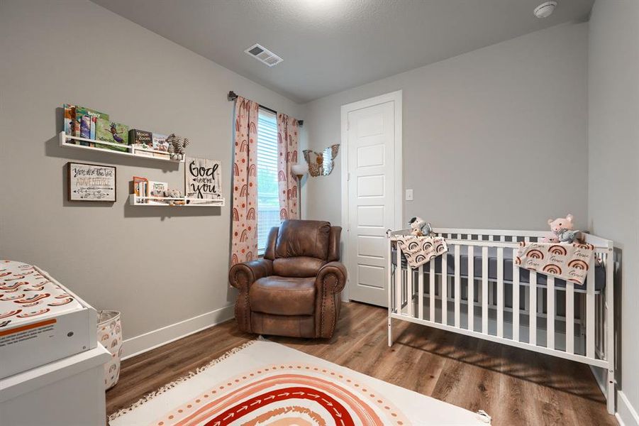 Bedroom featuring wood-type flooring and a nursery area