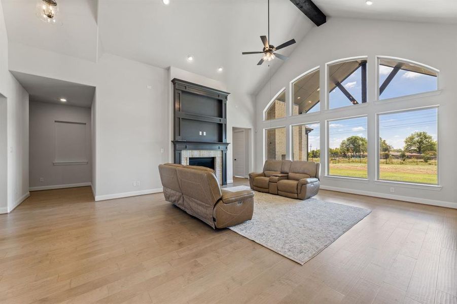 Living room featuring a fireplace, ceiling fan, light hardwood / wood-style flooring, and high vaulted ceiling