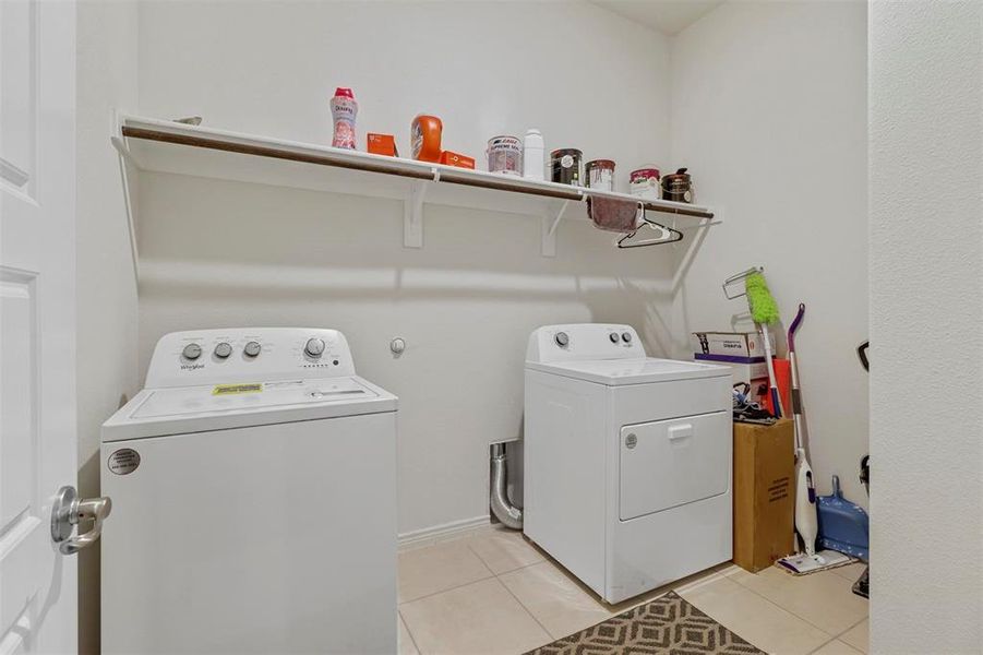 Washroom featuring washer and clothes dryer and light tile flooring