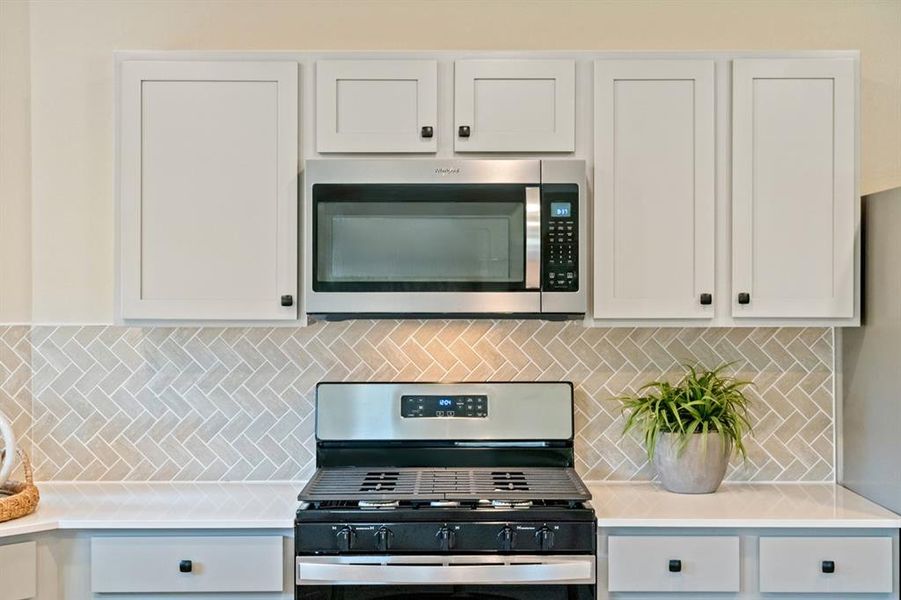 This kitchen will not disappoint! Featuring stained wood cabinets, silestone countertop, custom modern backsplash, stainless steel appliances, and warm custom paint.