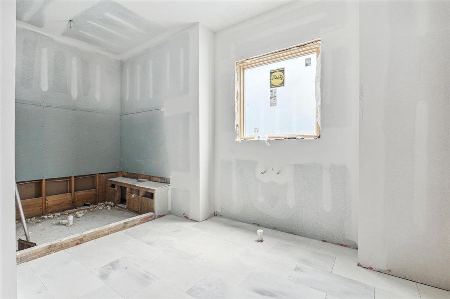 Alternate view of the primary bath toward what will soon be a spa-like shower and soaking tub area.  The gorgeous marble floor tile has already been completed.  Photo as of 9/3/2024