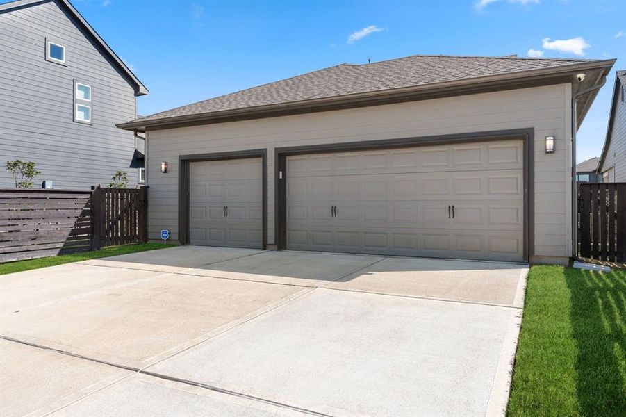 Three car garage with large driveway, located in the rear of the home.  Coach lights on light sensor and security camera stays with the home.