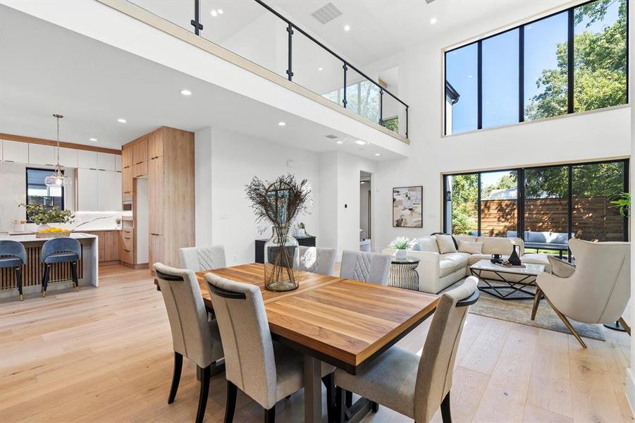 Dining space featuring a towering ceiling and light hardwood / wood-style floors