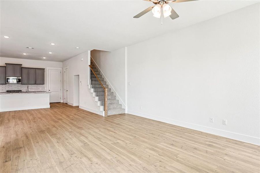 Unfurnished living room with ceiling fan, light hardwood / wood-style flooring, and sink