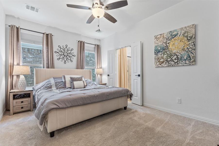 Bedroom with multiple windows, light colored carpet, and ceiling fan