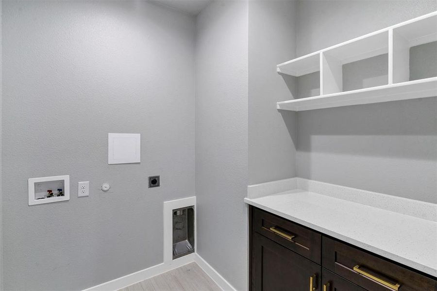 Clothes washing area with hookup for a washing machine, hookup for an electric dryer, light hardwood / wood-style flooring, cabinets, and gas dryer hookup