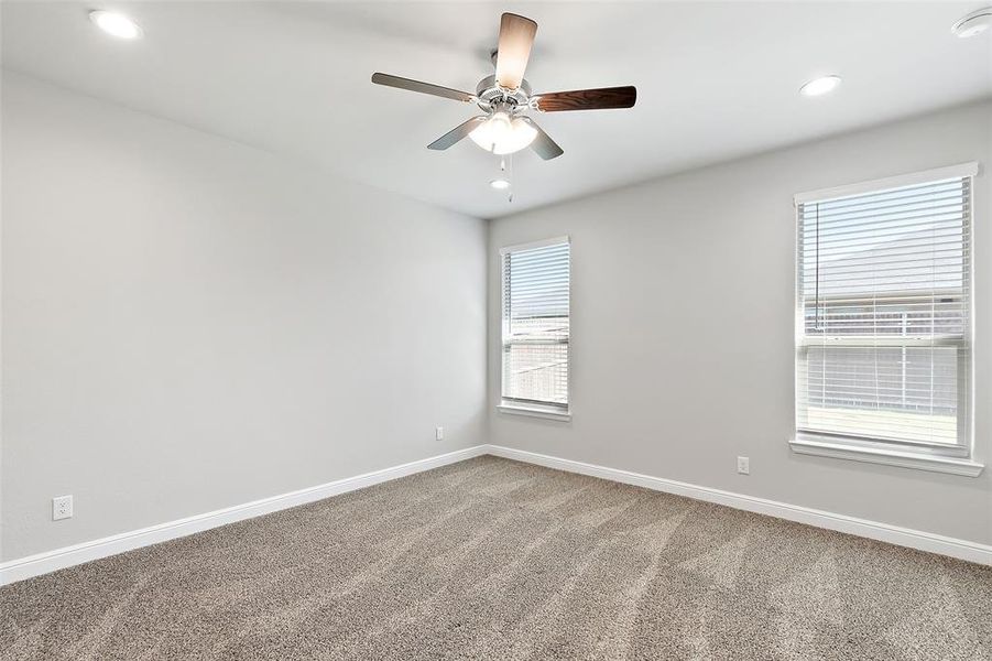 Unfurnished room with ceiling fan, a healthy amount of sunlight, and carpet floors