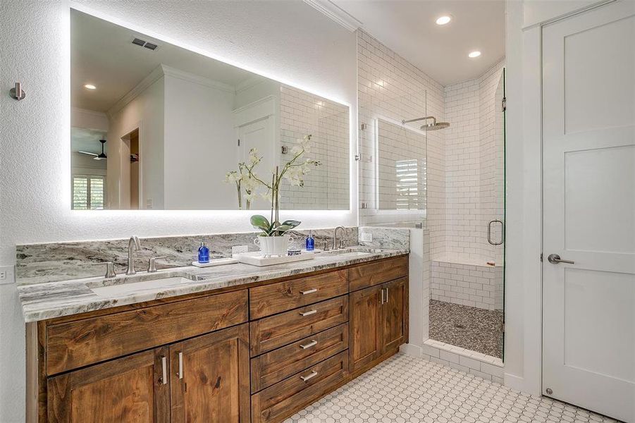 Bathroom featuring tile patterned floors, a shower with door, crown molding, and vanity.