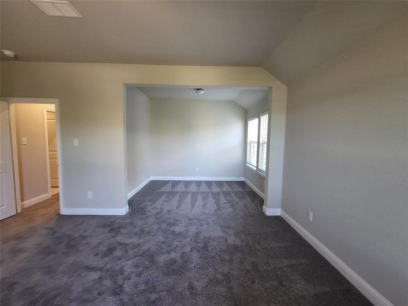 Carpeted empty room featuring lofted ceiling