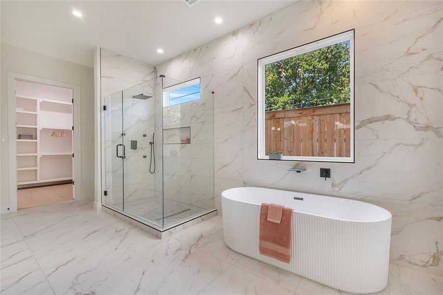 Bathroom with a wealth of natural light, tile patterned flooring, and tile walls