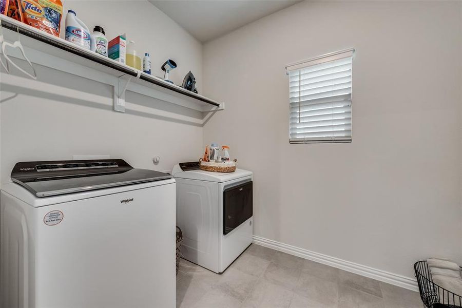 Laundry room featuring washing machine and clothes dryer and light tile flooring