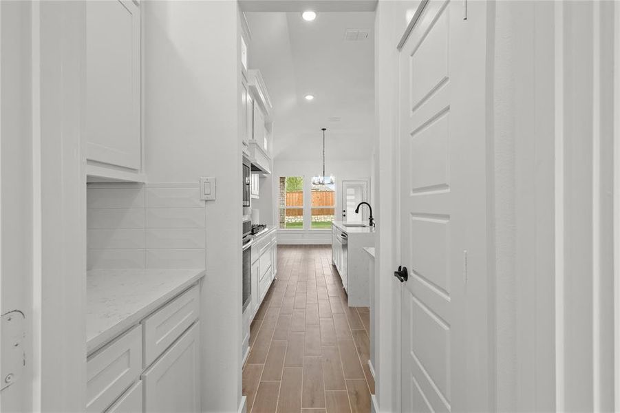 Corridor with sink, light wood-type flooring, and an inviting chandelier