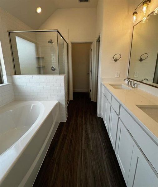 Bathroom with independent shower and bath, vanity, lofted ceiling, and wood-type flooring