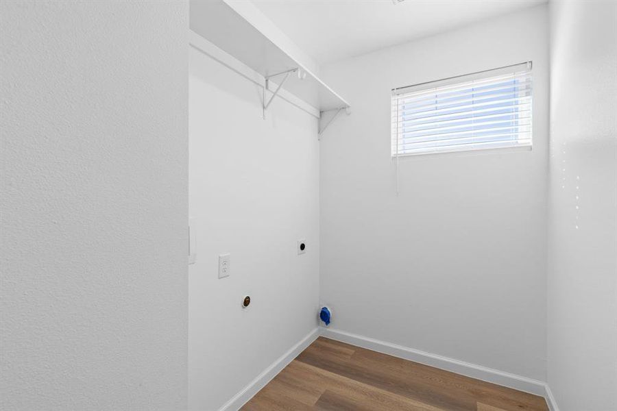 Washroom with hardwood / wood-style flooring and hookup for an electric dryer