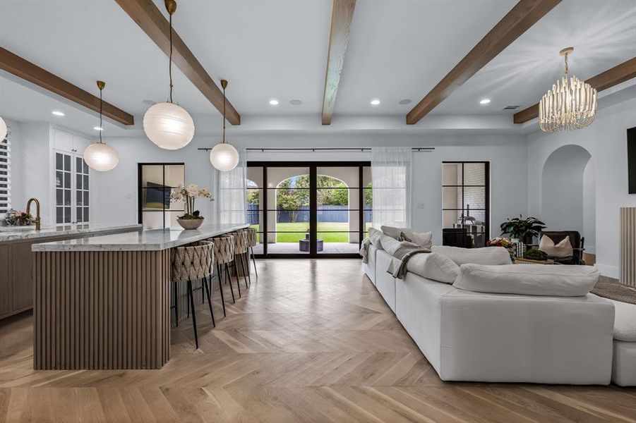 Living room featuring light parquet floors, an inviting chandelier, french doors, beam ceiling, and sink