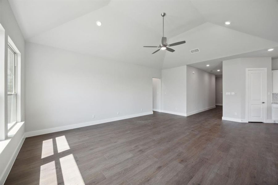 Unfurnished living room with dark hardwood / wood-style flooring, high vaulted ceiling, and ceiling fan