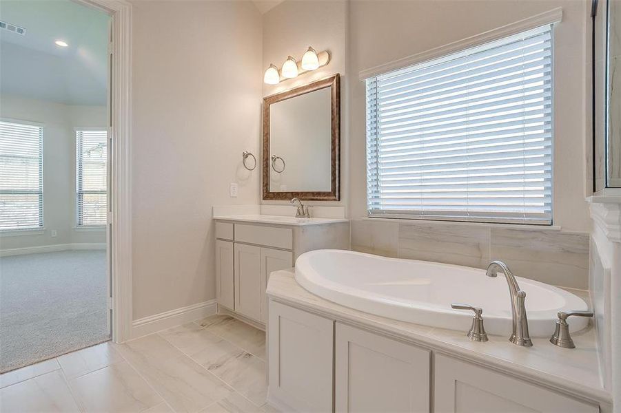 Bathroom featuring tile patterned flooring, a bathtub, and vanity