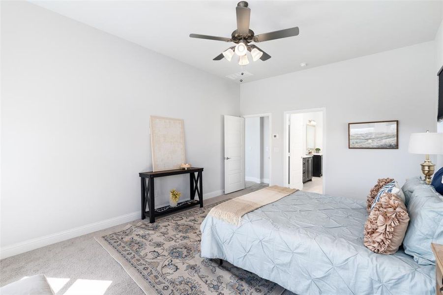 Bedroom with ceiling fan, ensuite bath, and light carpet