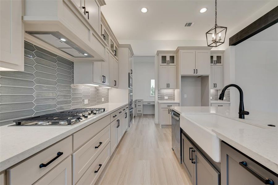 Kitchen featuring hanging light fixtures, light wood-type flooring, light stone counters, a chandelier, and premium range hood