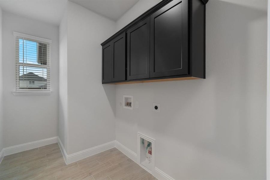 Washroom with light wood-type flooring, washer hookup, cabinets, and electric dryer hookup