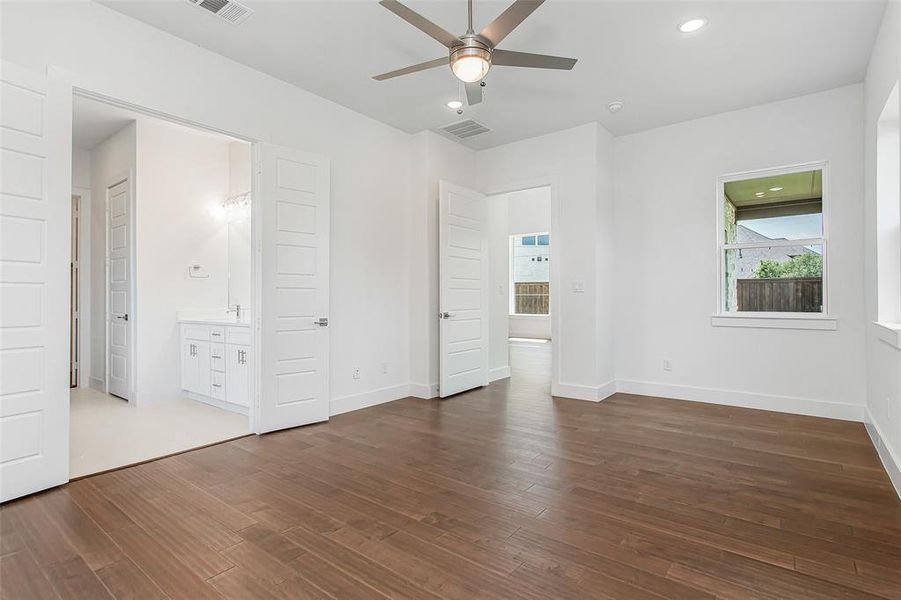 Unfurnished bedroom with dark wood-type flooring, connected bathroom, and ceiling fan