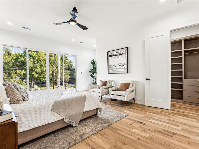 Bedroom with a spacious closet, a closet, light hardwood / wood-style flooring, and ceiling fan