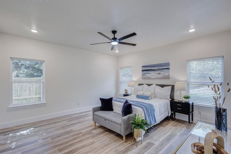 Bedroom with light wood-type flooring, multiple windows, and ceiling fan