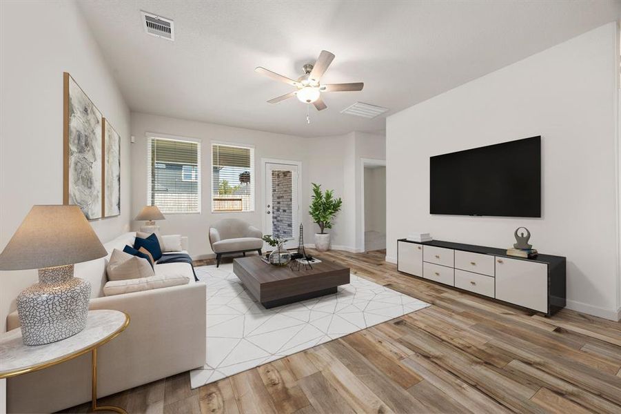 This inviting living room offers the perfect combination of style and comfort, featuring beautiful wood-look EVP flooring and bathed in natural light from large windows making the space feels bright and airy. The neutral color palette and modern ceiling fan create a cozy atmosphere, while the open layout makes it ideal for both relaxing and entertaining.