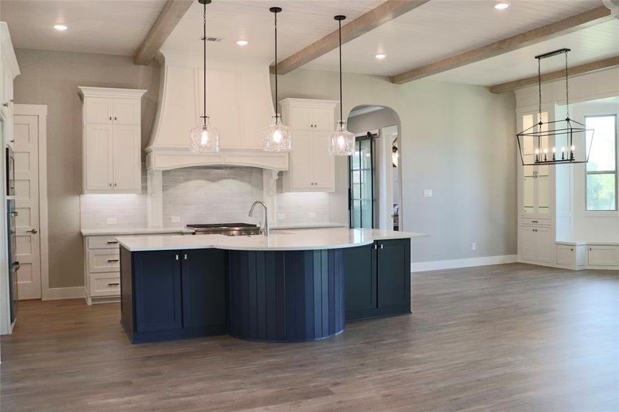 Kitchen featuring white cabinets, hanging light fixtures, hardwood / wood-style flooring, and beam ceiling