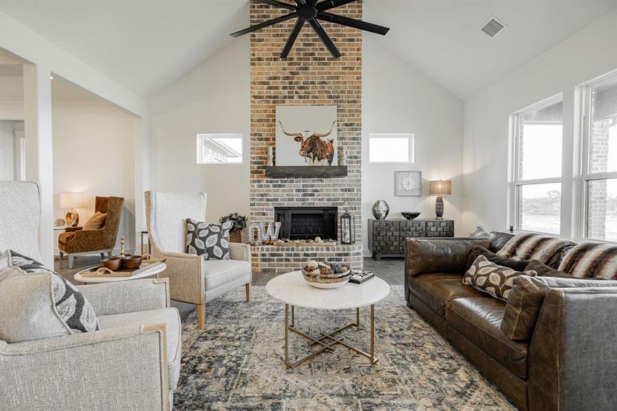 Living room with high vaulted ceiling, ceiling fan, and a fireplace