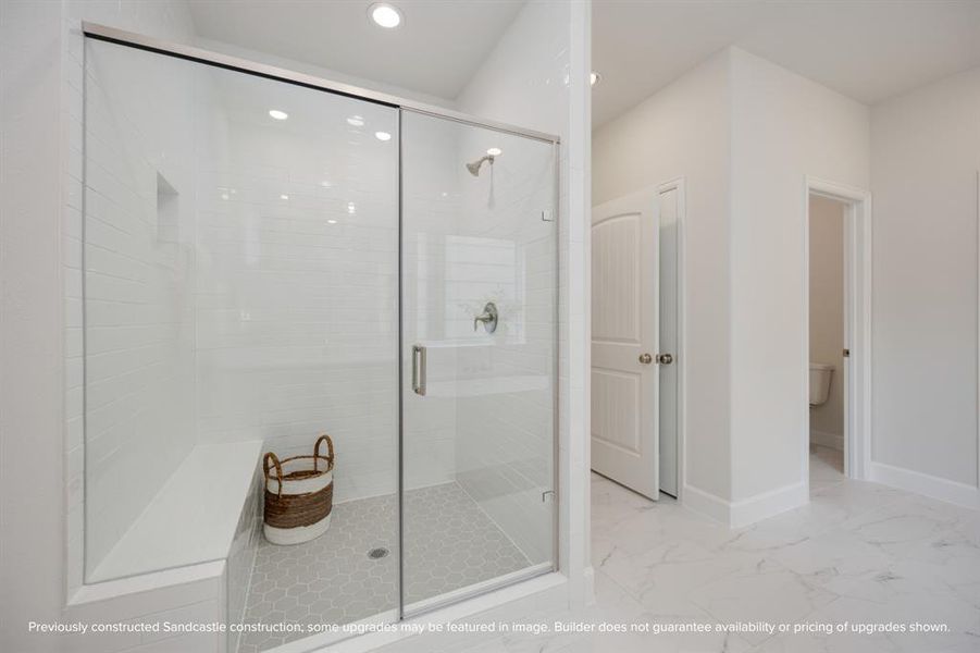 A large, step-in shower with bench seating and a separate water closet redefine luxury, making every morning a spa-like experience.