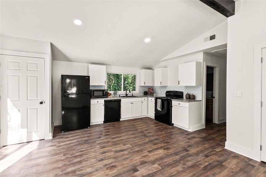 Kitchen featuring sink, black appliances, white cabinetry, and dark wood-type flooring