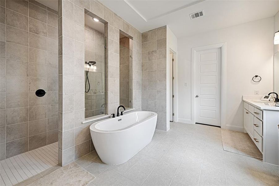 Bathroom featuring independent shower and bath, vanity, tile patterned floors, and tile walls