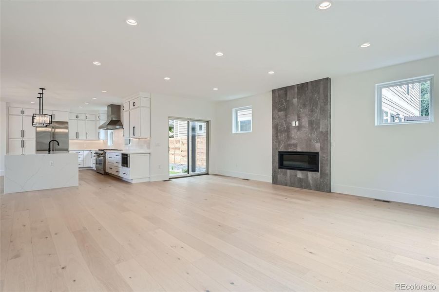 Expansive great room centered around a linear fireplace accent wall while seamlessly transitioning to dual outdoor spaces creating an inviting indoor-outdoor living experience.