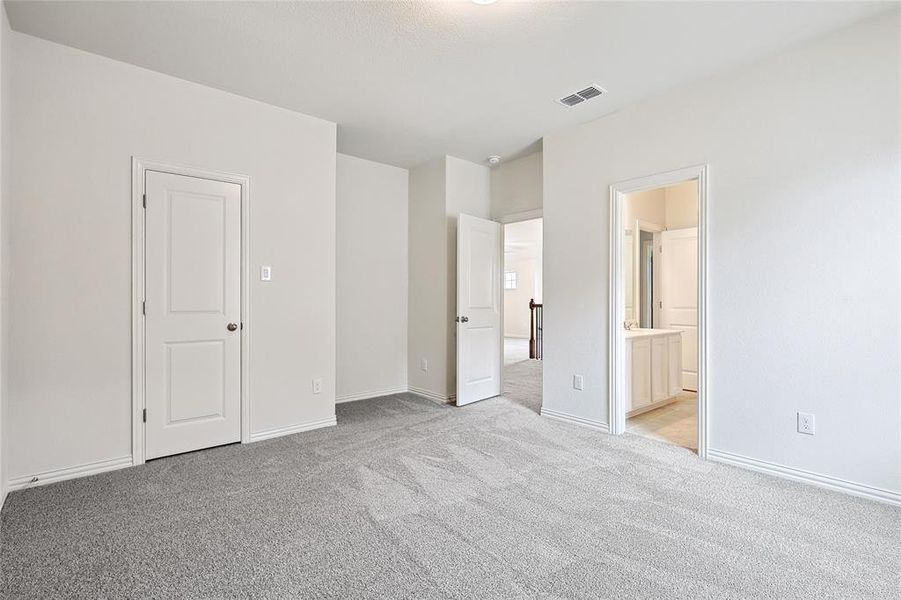 Unfurnished bedroom with ensuite bath and light carpet