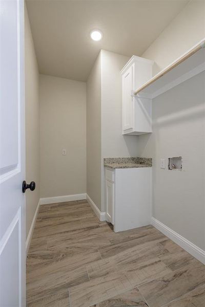 Laundry area featuring hookup for a washing machine, cabinets, and light wood-type flooring