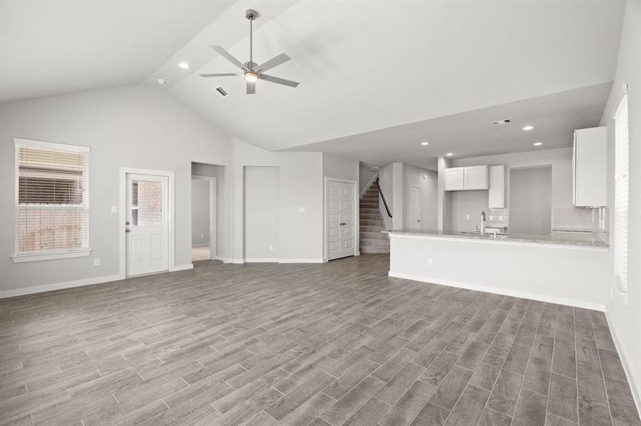 Bring your loved ones and guests together in the inviting living room! Boasting lofty high ceilings, recessed lighting, a stylish ceiling fan, custom paint, stunning flooring, and expansive windows that flood the space with ample natural light all day long. Sample photo of completed home with similar floor plan.