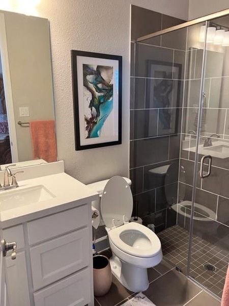 Bathroom with oversized vanity, tile floors, toilet, and walk in shower