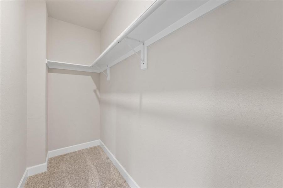 This is a clean, empty walk-in closet with built-in shelving, offering ample storage space and a neutral color scheme to complement various decors.