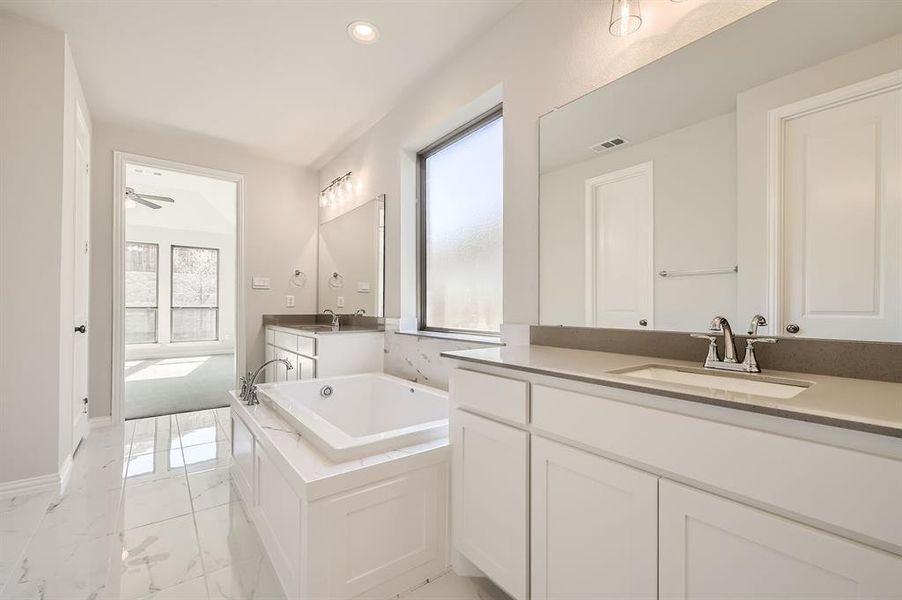 Bathroom with a wealth of natural light, vanity, a bathtub, and ceiling fan